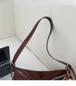 Détail du sac à bandoulière en daim marron foncé avec sangle réglable et zip métallique