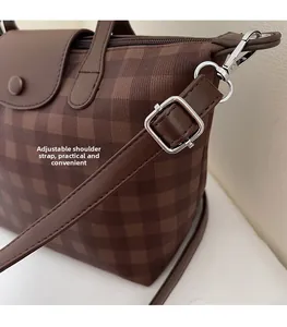 Close-up of adjustable shoulder strap and metal hook on brown plaid tote bag
