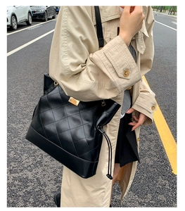 Close-up of black quilted leather tote bag with gold hardware and drawstring side detail
