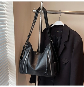 Detail of black matte leather large hobo bag with silver zipper accents on display rack