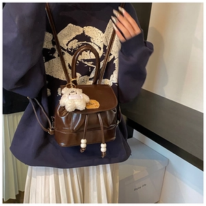 Detail view of vintage dark brown PU leather mini backpack with plush bear charm