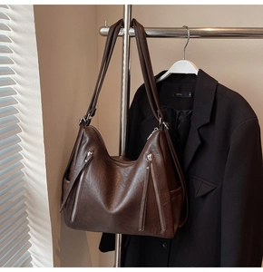Detail of dark brown faux leather tote featuring vertical zippers and soft pleated texture