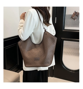Close-up of deep brown woven leather bag with KENEDDI logo and premium texture