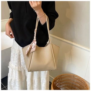 Dettaglio della grande borsa tote beige con foulard di seta geometrico rosa sul manico