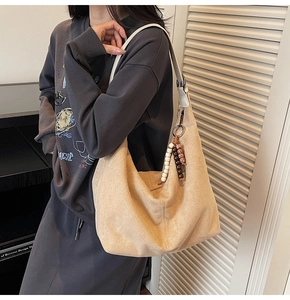 Detail of a beige suede hobo bag featuring retro beads and a wide shoulder strap