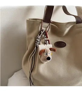 Detail of plush dog keychain with leather mount on a beige canvas tote bag