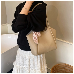 Dettaglio della borsa tote beige con trama litchi ed elegante sciarpa di seta decorativa