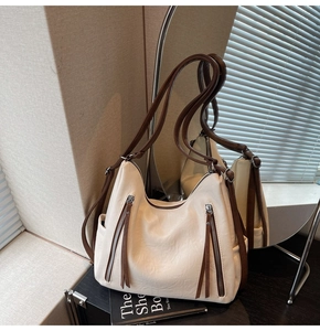Close-up of retro cream tote bag with contrast brown tassels and side pocket detail