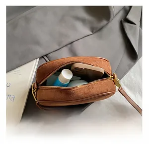 Internal capacity of the brown suede crossbody bag showing phone and cosmetics space