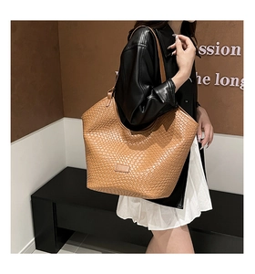 Close-up of the brown woven PU leather texture and rectangle brand patch on hobo tote bag