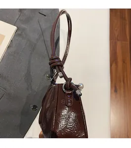Détail du sac nuage plissé marron brillant avec perle et poignée à nœud élégante