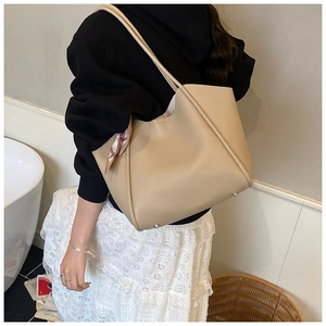 Dettaglio della borsa tote in pelle beige con foulard floreale e piedini in metallo