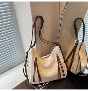 Detail of cream white tote bag featuring vertical brown zipper pullers and large side pockets