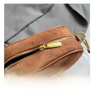 Close-up of golden metal zipper and brown suede material on vintage crossbody bag