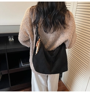 Detail of black suede hobo bag with vintage beaded tassel on a model's shoulder