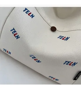 Detail der cremefarbenen Canvas-Tasche mit rot-blauer TELN-Stickerei und Knopfverschluss
