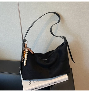 Détail du sac hobo en daim noir avec perles décoratives en bois marron et jaune
