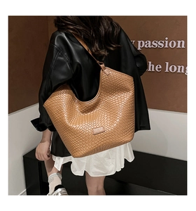 Detail of caramel brown woven tote bag featuring fine cross-weave texture and logo patch