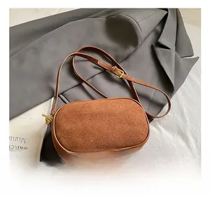 Close-up of brown matte crossbody bag on a grey blazer with minimalist gold hardware