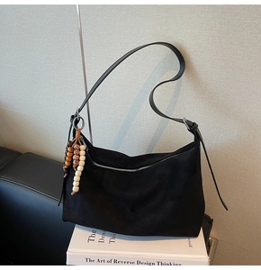 Détail du sac hobo en daim noir avec bandoulière en cuir et pendentif perles bohème