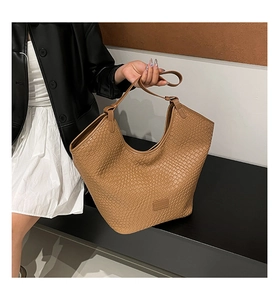 Close-up of brown woven texture tote bag with brand logo and premium soft material