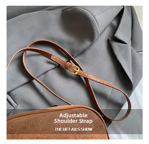 Detail of adjustable strap with vintage gold buckle on brown suede square bag