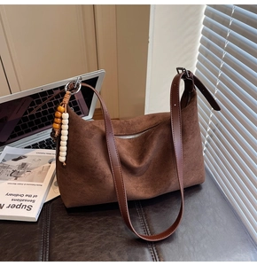 Détails de texture du sac dumpling en daim marron foncé avec pompon perlé décoratif