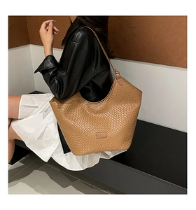 Detail of woven texture on a brown hobo bag worn by a model in modern attire