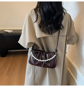 Detail of burgundy glossy patent leather bag with large white pearl handle decoration