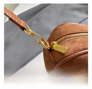 Detail view of premium golden hardware hook on brown frosted suede crossbody bag