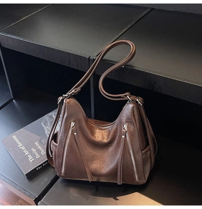 Detail of dark brown vintage faux leather tote with tassel zippers on display rack