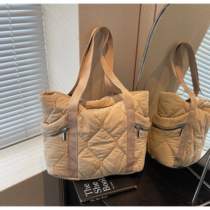Detail of quilted tote bag with large diamond patterns and dual metal zipper pockets