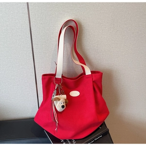 Detail of red canvas tote bag with leather straps and cute plush puppy charm