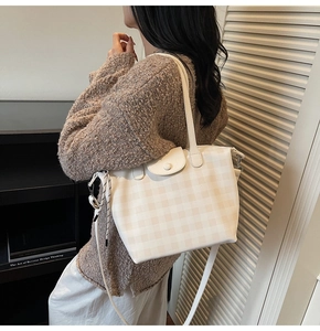 Detail of the cream checkered tote bag showing the texture, handle, and adjustable strap