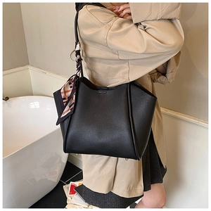 Dettaglio borsa tote in pelle nera martellata con foulard di seta colorata sul manico