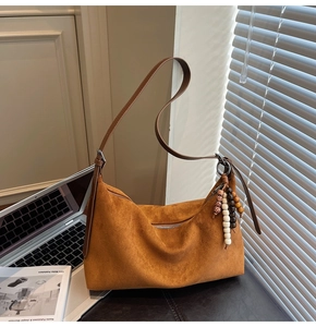 Détail du sac hobo en daim marron avec perles décoratives en bois à motif léopard