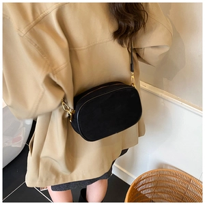 Minimalist black matte oval crossbody bag with gold hardware worn by model side view