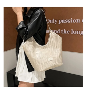 Detail showing the intricate woven texture and designer patch on the cream tote bag