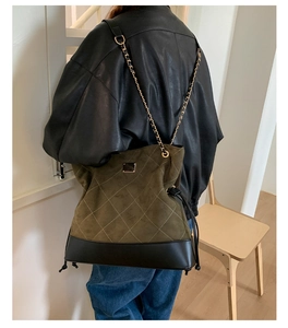 Close-up of olive green quilted suede tote with gold chain strap and drawstring detail