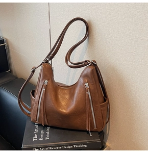 Detailed view of caramel brown tote bag featuring vertical zippers and leather tassels
