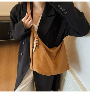Detailed close-up of brown suede Hobo bag with ethnic style beaded pendant on side