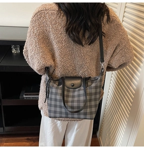 Detail showing the gray plaid fabric texture and black leather strap of this tote bag