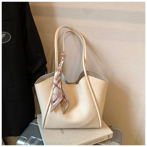 Dettaglio borsa tote beige con sciarpa geometrica e finitura in pelle martellata