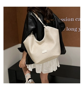 Close-up of beige woven hobo bag featuring fine texture and elegant shoulder strap detail