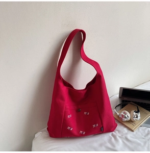 Detail einer roten Canvas-Tasche mit TELN-Stickerei und Vordertasche mit Metallschnalle