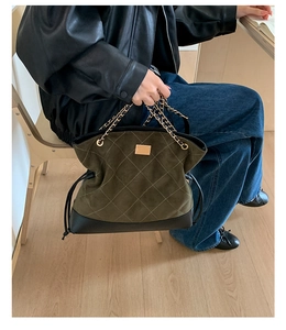 Detail of olive green quilted suede tote featuring gold chain handle and drawstring