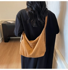 Detail of hobo crossbody bag in brown suede with ethnic wooden bead charm detail
