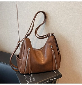 Detail view of brown vintage PU leather hobo bag featuring side pockets and zipper tassels