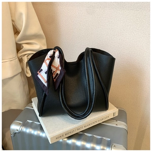 Dettaglio della borsa tote in pelle nera martellata con elegante sciarpa sul manico