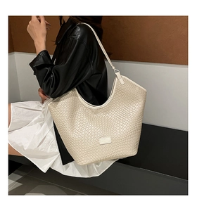 Detail of cream-white woven texture and embossed logo on minimalist hobo tote bag